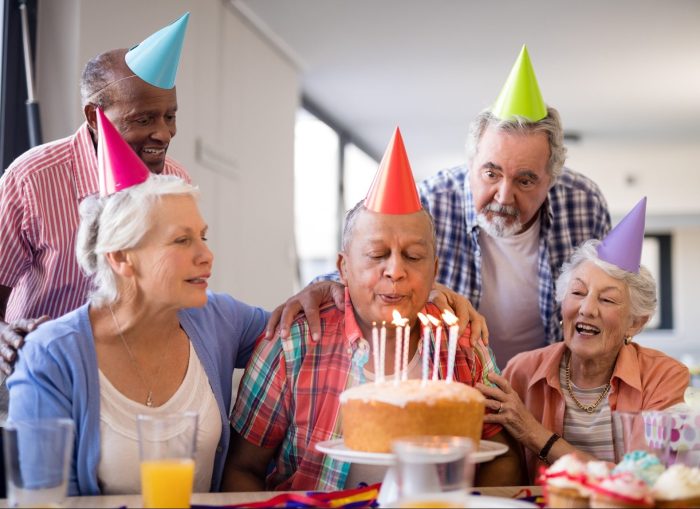 Happy seniors gathered around a table to celebrate a birthday party